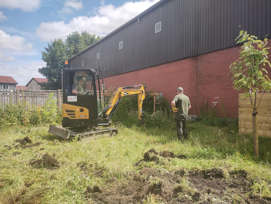 click to see larger image digging the pond in the community garden